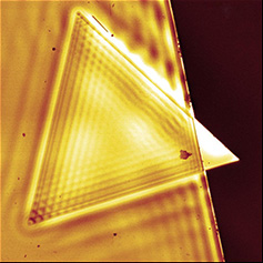 Graphic of a gold stripe with gold triangle on it with its corner peeping out