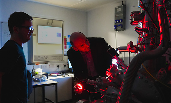 Researchers examining advanced scientific instrumentation in a laboratory.