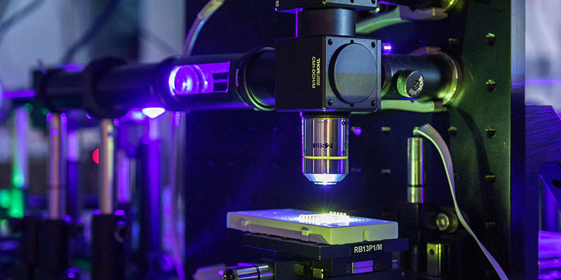Photonics lab equipment illuminated in blue and green light 