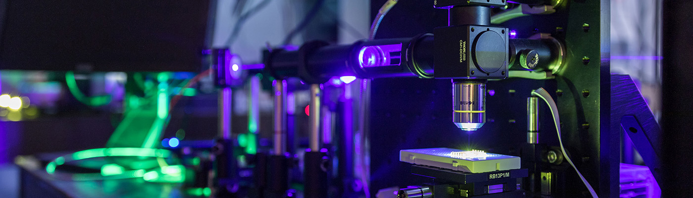 Photonics lab equipment illuminated in blue and green light 