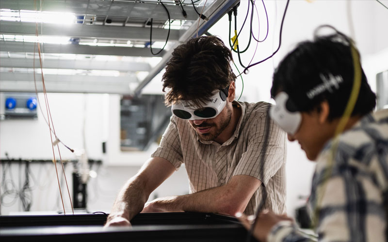 Researchers wearing protective eyewear working together in a laboratory.